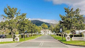 A street view with a large building in the background, trees lining the road, and a sign that reads 'SILVERADO'. - Napa 2BR Silverado condo — two king suites, fireplace & pool (Napa)