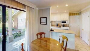 A compact kitchen with white cabinets, a central island, and a dining area with a round table and chairs. - Napa 2BR Silverado condos — two kings, full kitchen, golf views (Napa)