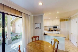 A compact kitchen with white cabinets, a central island, and a dining area with a round table and chairs. - Napa 2BR Silverado condo — two king suites, golf views & pool (Napa)