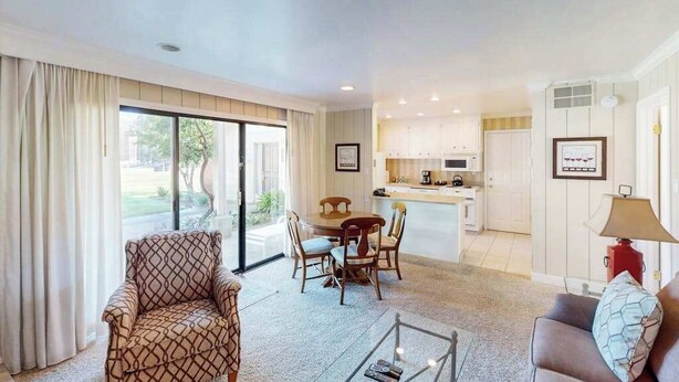 A living room with a sofa, a dining table with chairs, a kitchen area, and a sliding glass door leading to an outdoor area. - Napa 2BR Silverado condos — two kings, full kitchen, golf views (Napa)