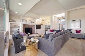 A modern living room with a fireplace, grey sofas, and a glass coffee table.