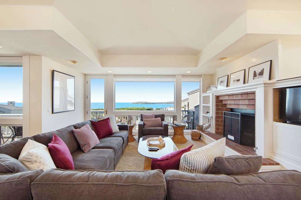 Panoramic ocean views flood the living room through floor-to-ceiling windows, creating your coastal living dream.