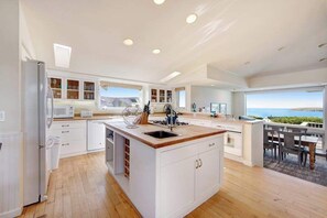 A modern kitchen with a central island, built-in cabinets, and a view of the ocean.
