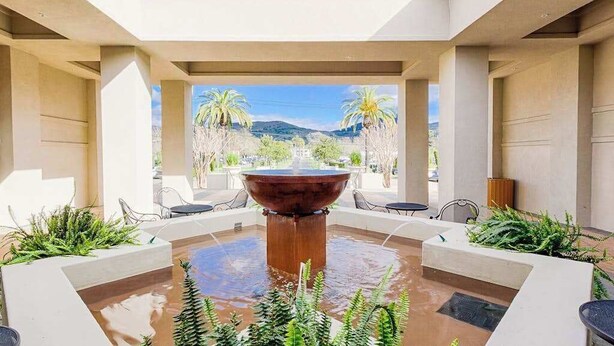 Un patio con una fuente central, zonas de estar y vistas a un paisaje montañoso.