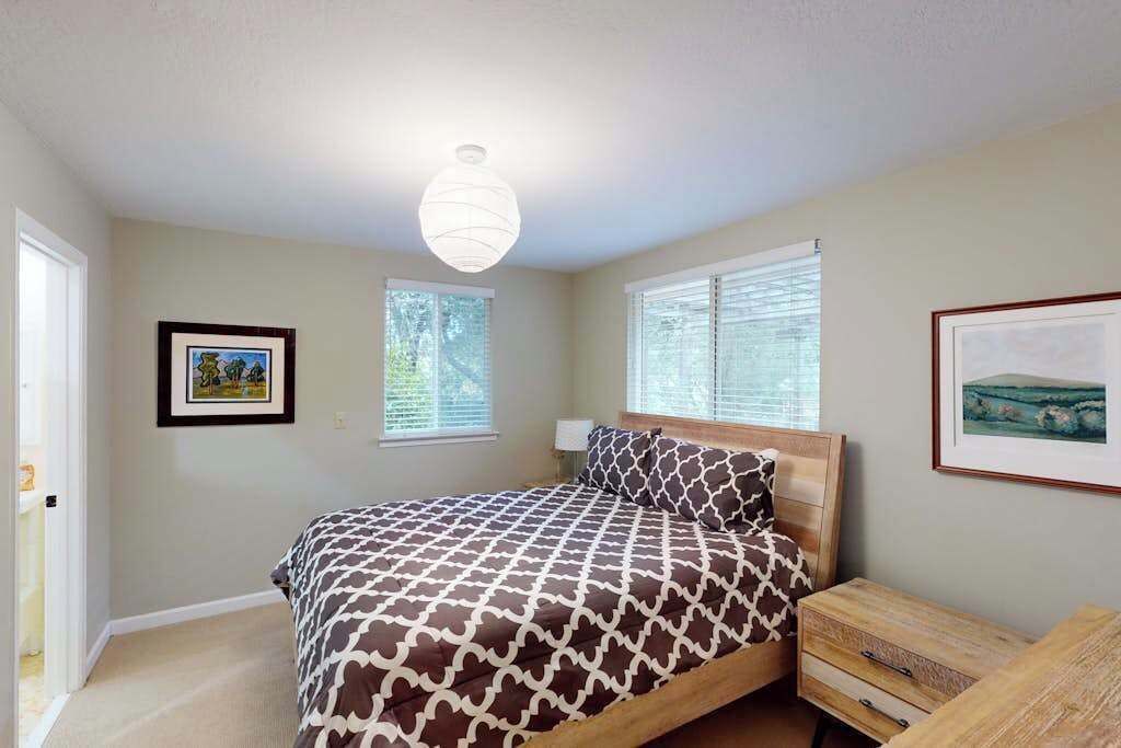 Une chambre à coucher avec un lit, des tables de chevet et des tableaux encadrés accrochés aux murs.