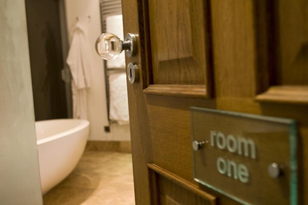 A bathroom with a white bathtub, a towel hanging on a rack, and a door labeled 'room one'.