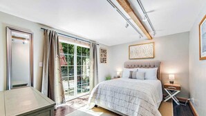 Een slaapkamer met een bed, nachtkastje en uitzicht op de omgeving.