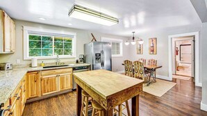 Een keuken met houten kasten, een centraal eiland en een eethoek met gestreept beklede stoelen.