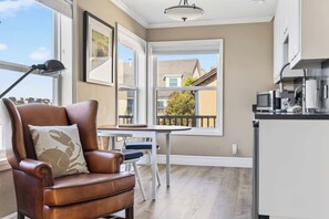 A modern kitchen with a dining area, a leather armchair, and a view of the neighborhood.