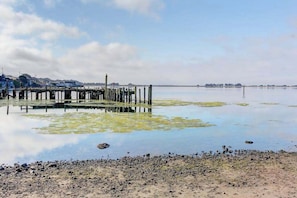 A waterfront scene with a pier extending into calm water, surrounded by a rocky shoreline.