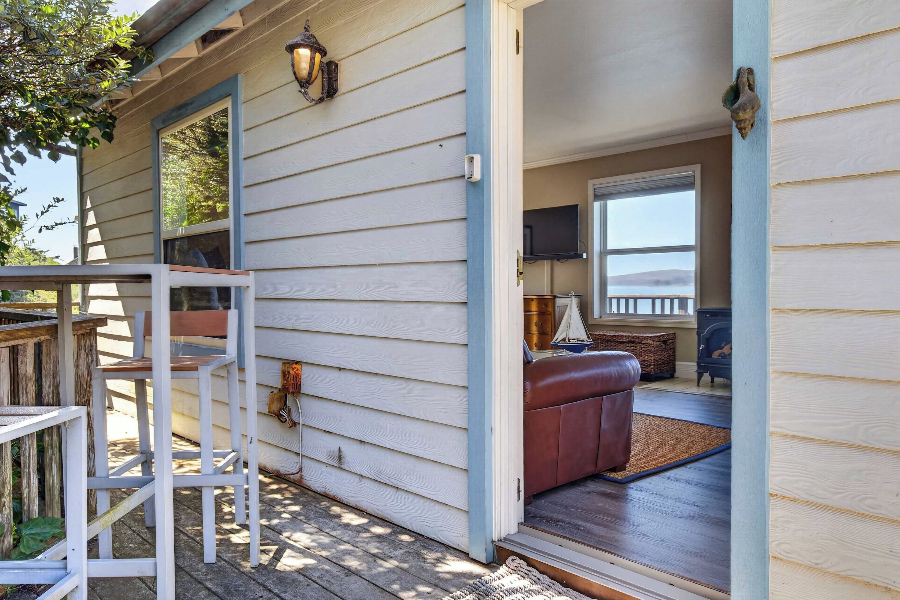 Une terrasse en bois avec une balustrade blanche, un banc en cuir marron et un téléviseur fixé au mur.