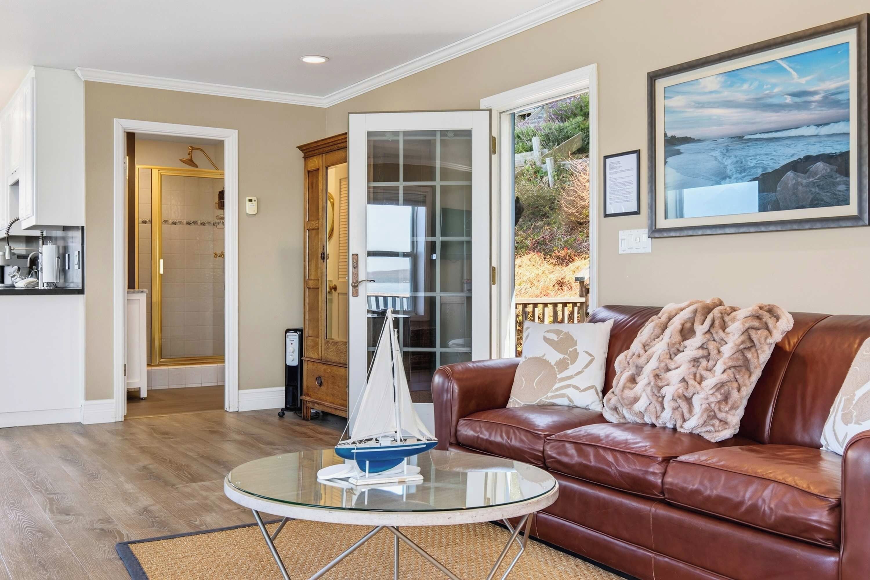 A living room with a leather sofa, a glass coffee table, and a sailboat model.