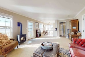 A spacious living room with a fireplace, a red leather sofa, a wooden cabinet, and a bookshelf.