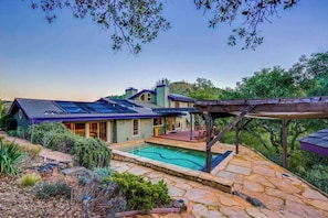 Une maison avec une piscine, un patio couvert et une terrasse en pierre.