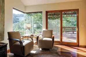 A room with two chairs, a table, and a large sliding glass door leading to an outdoor area.
