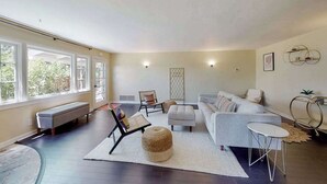 Ein geräumiges Wohnzimmer mit großem Fenster, einer Couch, einem Couchtisch und einer Bank.