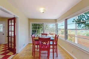 A dining area with a table and chairs, large windows, a door, and a wooden floor. - Healdsburg 2BR Fitch Mountain cottage with hot tub & river views (Healdsburg)