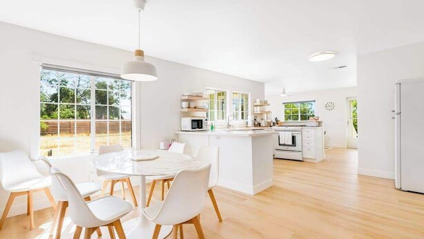 A modern kitchen with white cabinetry, a central island, and a dining area with white chairs. - Healdsburg 3BR vineyard farmhouse with game barn & wood fireplace (Healdsburg)