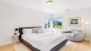 A bedroom with a large bed, bedside tables, a chair, and a window with a view. - Healdsburg 3BR vineyard farmhouse with game barn & wood fireplace (Healdsburg)
