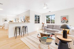 Una sala moderna con un sofá, una mesa de centro y un comedor con taburetes.