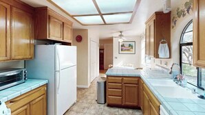A kitchen with wooden cabinets, a white refrigerator, a microwave, a sink, and a ceiling fan. - Cloverdale 3BR hillside lodge on 7 acres with hot tub & wave pool (Cloverdale)