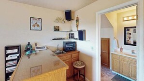 A compact kitchen with a wooden countertop, a sink, and a small stool. There is a shelf with various items and a speaker mounted on the wall. - Cloverdale 3BR hillside lodge on 7 acres with hot tub & wave pool (Cloverdale)