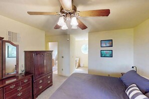 Ein Schlafzimmer mit einem Bett, einer Kommode, einem Deckenventilator und zwei Bildern an der Wand.