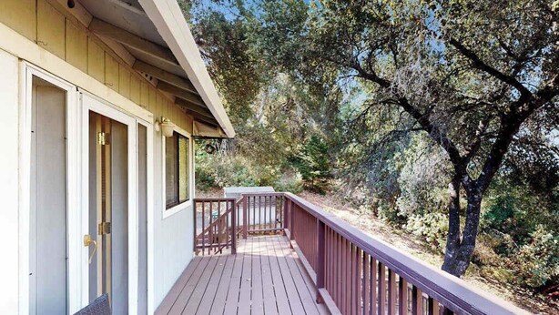 A wooden deck with a railing, a door, and a window. - Cloverdale 3BR hillside lodge on 7 acres with hot tub & wave pool (Cloverdale)