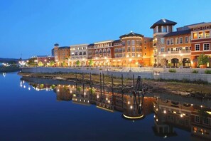 Un hotel frente al agua con varias construcciones, su reflejo en el agua y un puente que conecta las estructuras.