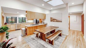 Een moderne keuken met houten kastjes, een groot eiland en een eethoek met banken.