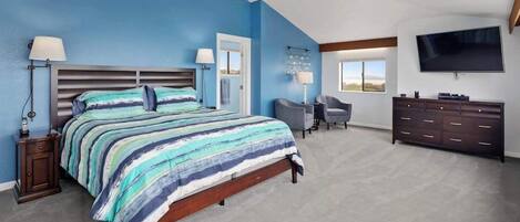 A bedroom with a bed, bedside tables, a desk, a chair, a dresser, and a TV.