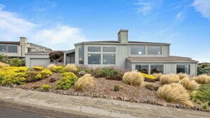 A modern two-story house with a landscaped garden featuring various shrubs and grasses. - Bodega Harbour Ocean-View Hot Tub Retreat (Bodega Bay)