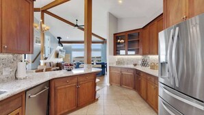 A modern kitchen with wooden cabinets, a stainless steel refrigerator, and a marble countertop. - Bodega Harbour Ocean-View Hot Tub Retreat (Bodega Bay)