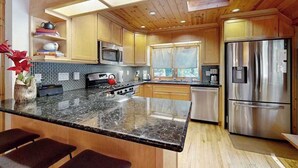 Eine moderne Küche mit Holzschränken, einem Edelstahlkühlschrank und einer Arbeitsplatte aus Granit.
