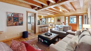 Ein geräumiger Wohnbereich mit Holzboden, eine Küche im Hintergrund und ein rotes Sofa.