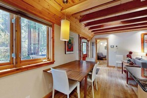 A wooden interior with a dining table, chairs, and a hanging light fixture. - Monte Rio 2BR A-frame cabin with private hot tub — dog friendly (Monte Rio)