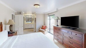 A bedroom with a bed, a TV, a dresser, a lamp, and a chair.