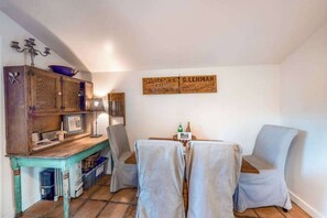 Ein Zimmer mit einem Holzkabinett, einem Tisch mit zwei Stühlen und einem an der Wand befestigten Schild.