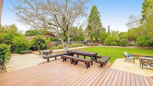 Une terrasse en bois avec des tables de pique-nique et une pelouse.