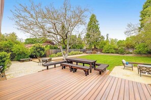 A wooden deck with picnic tables and a lawn.