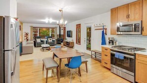Een moderne keuken met houten kastjes, roestvrijstalen apparatuur en een eethoek met blauwe stoelen.