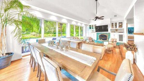 A modern living room with a dining area, large windows, a fireplace, and a ceiling fan. - Sonoma 4BR wine country estate on 6 acres — pool, hot tub, sleeps 14 (Sebastopol)