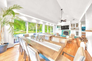 Una sala de estar moderna con comedor, ventanas amplias, chimenea y ventilador de techo.