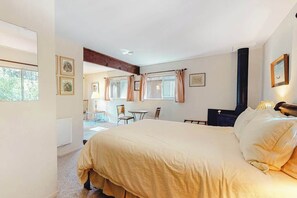 A bedroom with a large bed, a desk, chairs, and a fireplace. - Redwood Lodge - A-Frame on the Russian River (Monte Rio)