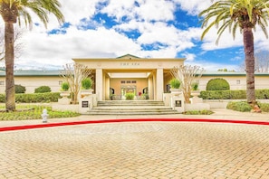 A building with a sign reading 'THE SPA' at the entrance, surrounded by palm trees and a paved walkway. - Napa 1BR Silverado condo with two patios, fireplace & pool access (Napa)