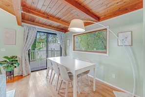 A dining area with a wooden ceiling, a white table, and chairs.