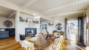 A spacious living area with a wooden dining table, white walls, and a fireplace. - Bodega Bay 2BR oceanfront cottage above Carmet Beach — dog friendly (Bodega Bay)