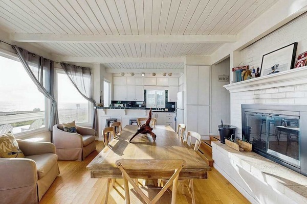 Enjoy dinner by the wood-burning fireplace in your open-concept living and dining space with ocean glimpses