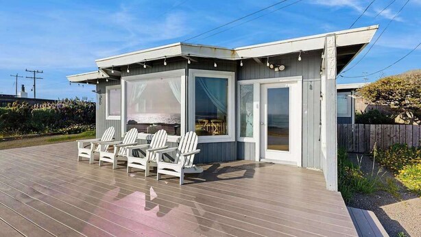 A modern house with a deck, white chairs, and a covered outdoor area. - Bodega Bay 2BR oceanfront cottage above Carmet Beach — dog friendly (Bodega Bay)