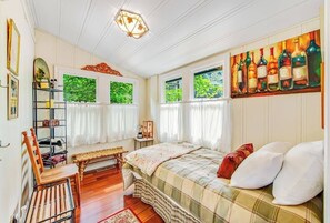 Ein Schlafzimmer mit einem Bett, einer Bank, einem Regal mit Gegenständen und einem Bild an der Wand.